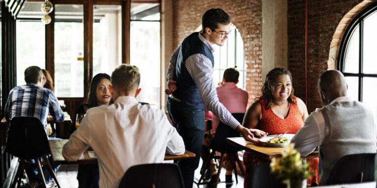 server serving food to couple at restaurant