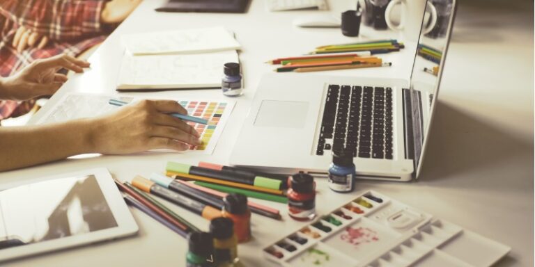 woman with colored pencils and paints designing a logo