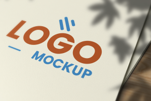 Two papers are on the table with 'Logo Mockup' written on them