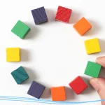 Person selecting from a circle of small colorful wooden squares