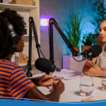 An interviewer is sitting at the table with a guest and making content on a podcast platform