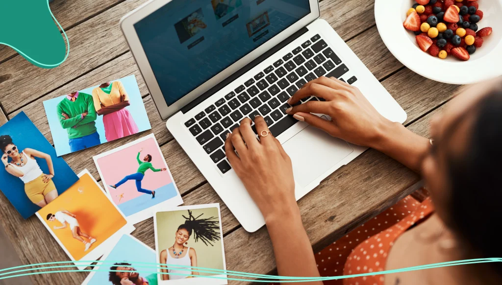 Woman working on a laptop and looking at photos on a desk