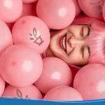Woman in a pink wig laying in a pool of pink balloons