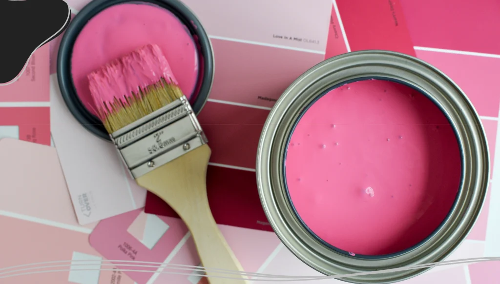Open can of pink paint with a paintbrush and pink paint swatches