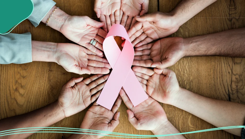 Group of diverse hands holding pink ribbon together representing breast cancer awareness and support