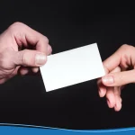 Close-up partial view of male and female hands holding blank card isolated on black