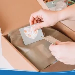 Cropped photo of businesswoman hands packing, preparing parcel for delivery package to buyer