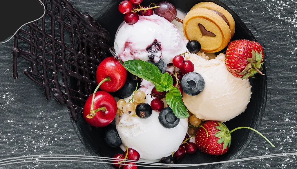 Vanilla ice cream scoops with fresh berries on black plate