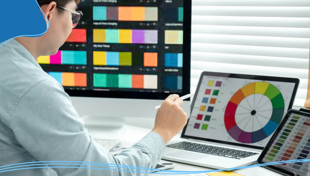 Male graphic designer is choosing color swatch samples on multiple screens and sketching on tablet