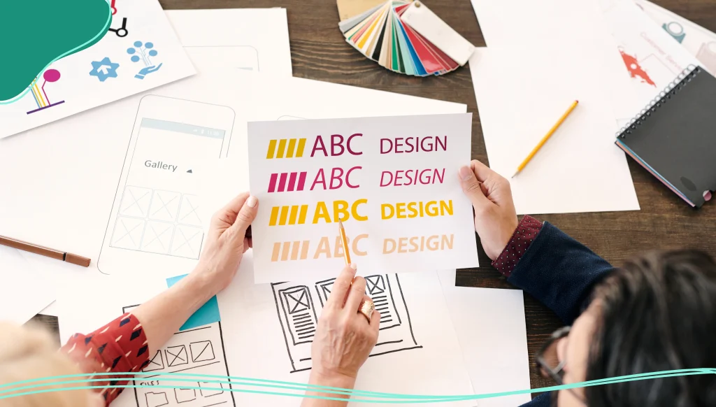 Hands of a female designer pointing at paper with letters and words