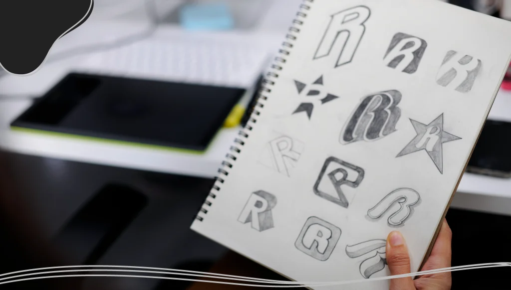 Hand holding a notebook with logo sketches