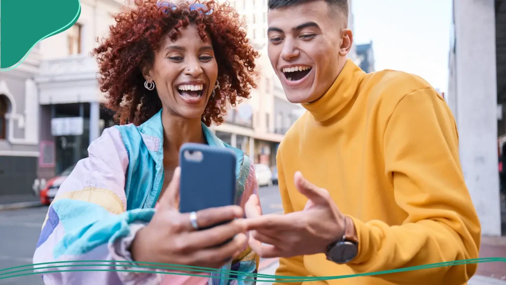 Two people smiling while looking at their phone