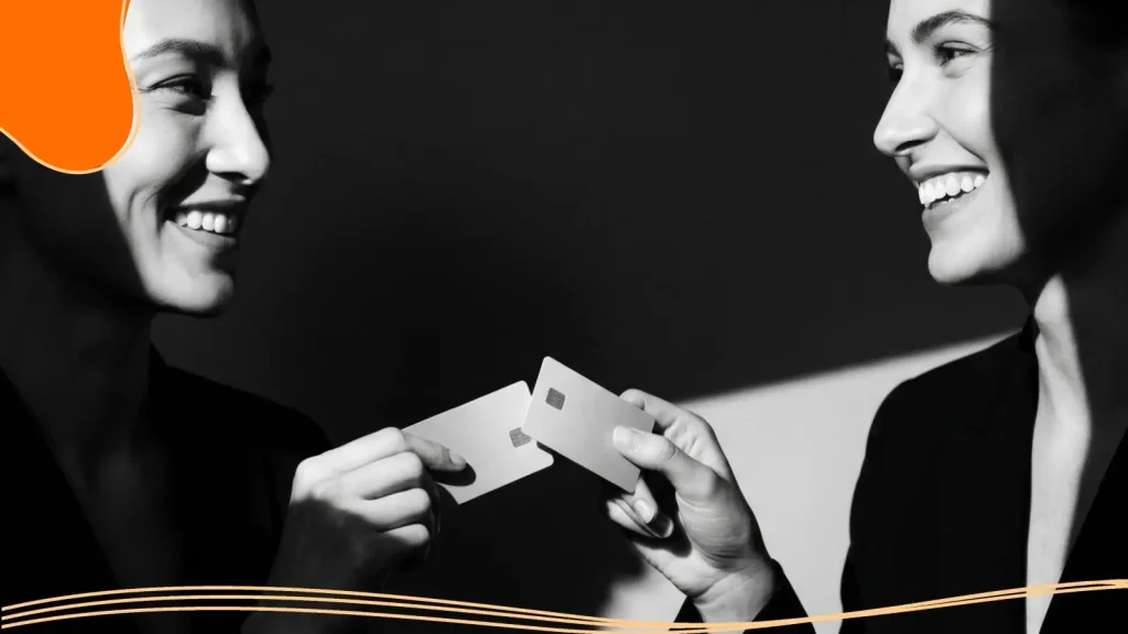 Two women exchanging their NFC-based business cards that look like credit cards.