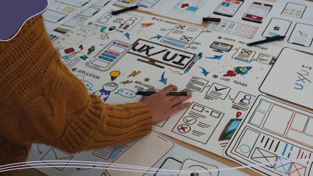 Someone works at a table planning and sketching a website, preparing to create a brand online.