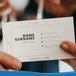 Close-up of two people exchanging a crisp white card at a networking event, highlighting how Are Business Cards Still Relevant in modern professional settings.
